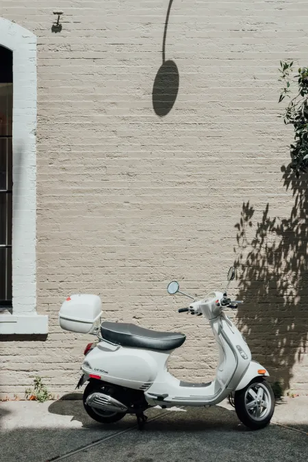 witte bromfiets tegen gevel