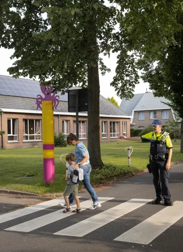 Inspecteur laat kind en moeder oversteken in schoolomgeving