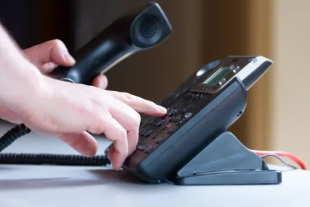 Hand toetst nummer in op telefoon
